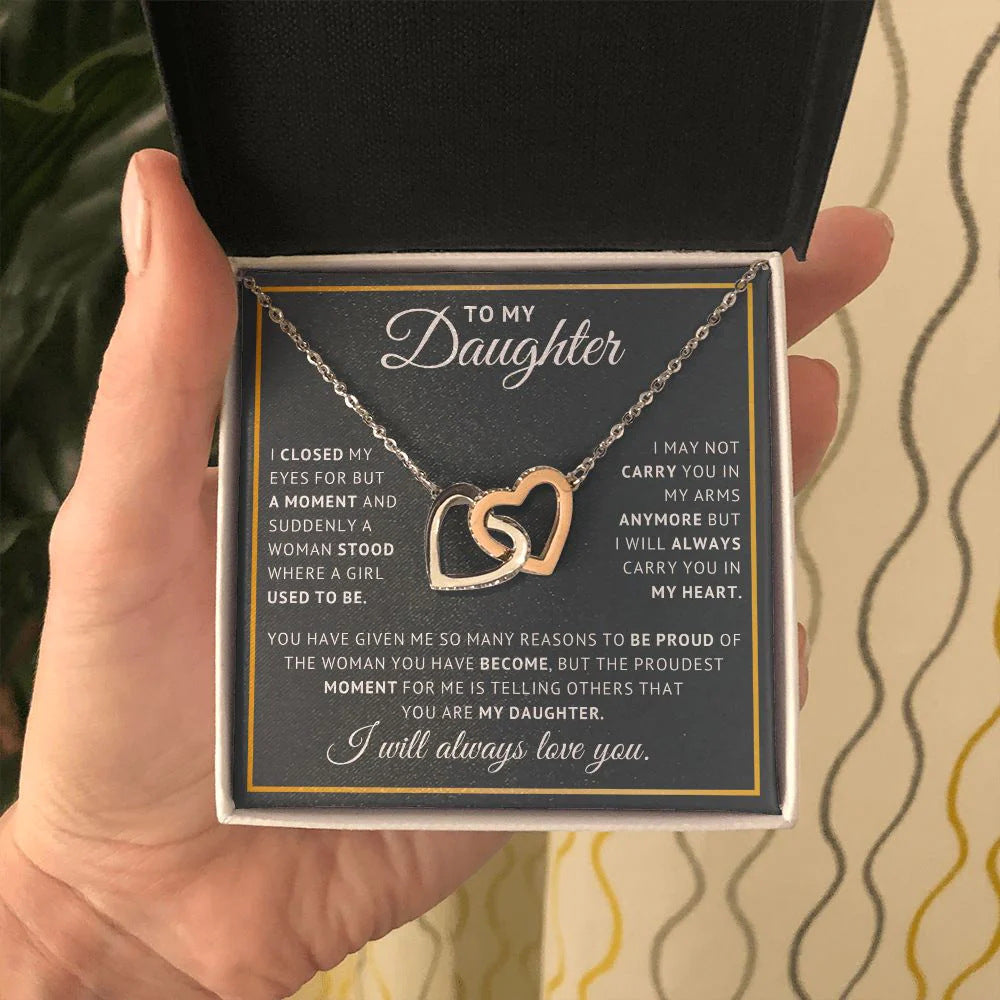Hand holding The Always Connected Hearts necklace with 'To My Daughter' card in a classic gift box
