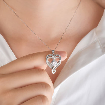 Woman holding The Eternal Heart silver pendant at her collarbone