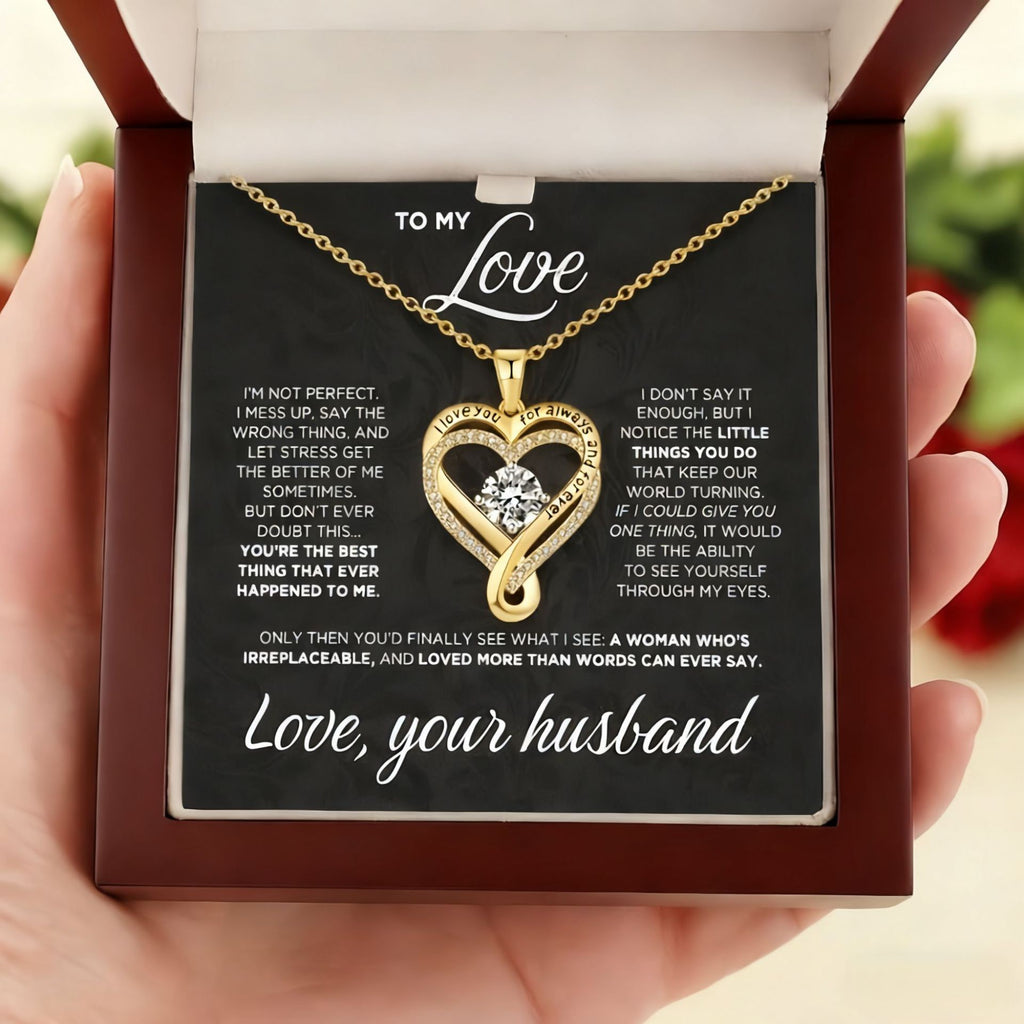Gold heart-shaped necklace with a message card held by a hand