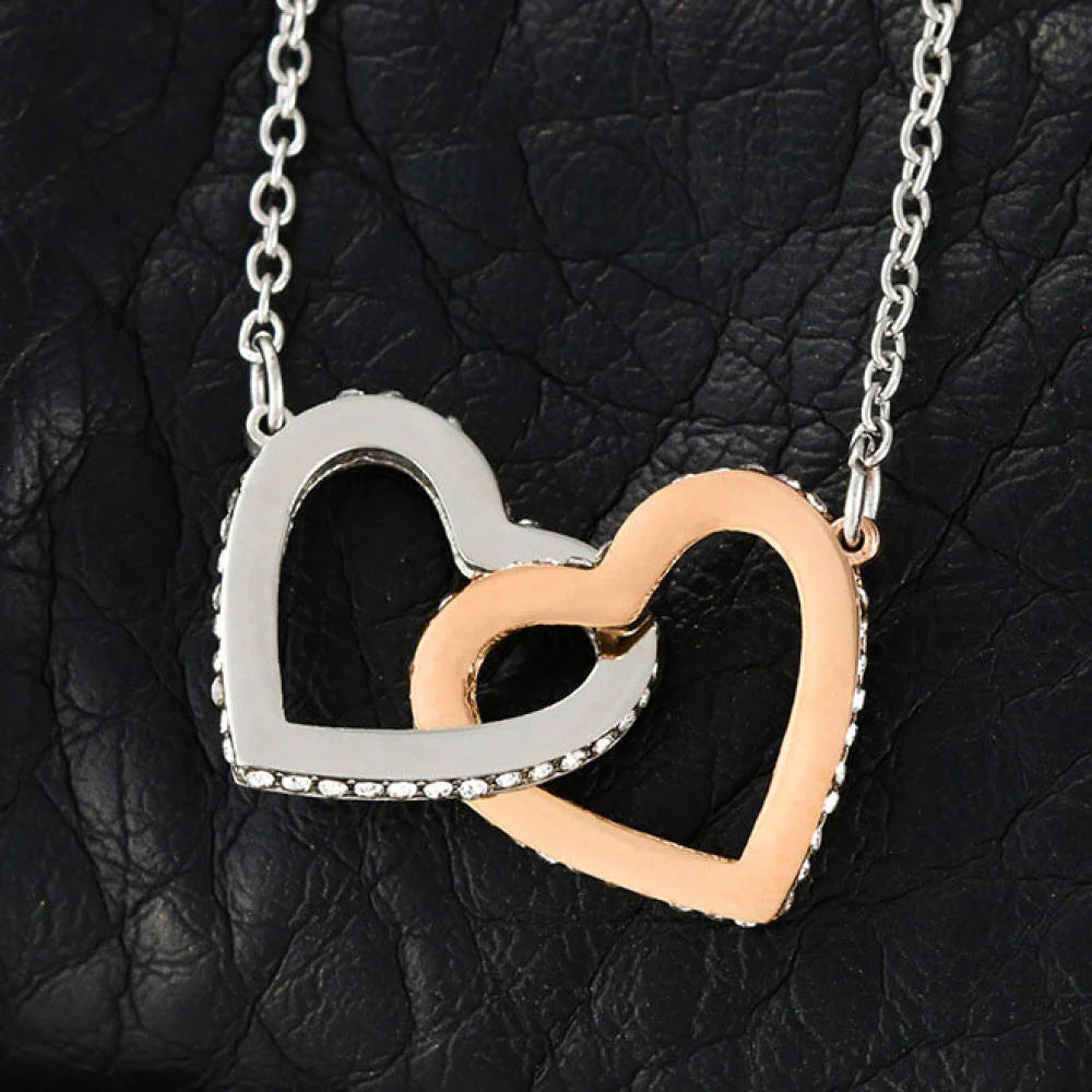 Close-up of interlocking silver and rose gold heart pendant with crystal accents